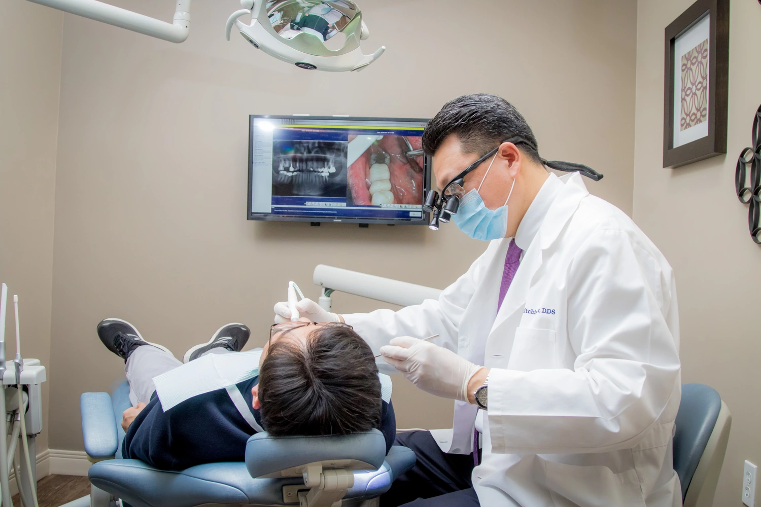 BlessedSmile-0061 A man in a white coat is seated as a dentist conducts a dental examination.